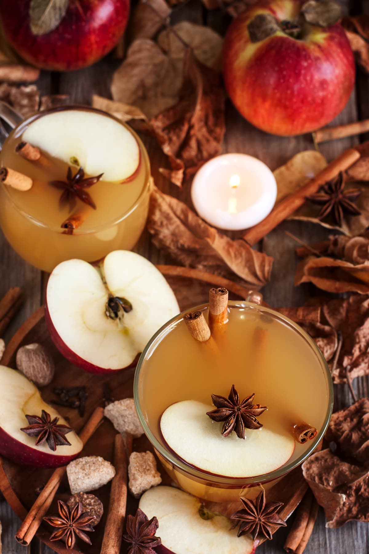 rustic fresh apple cider with apples and leaves on wood
