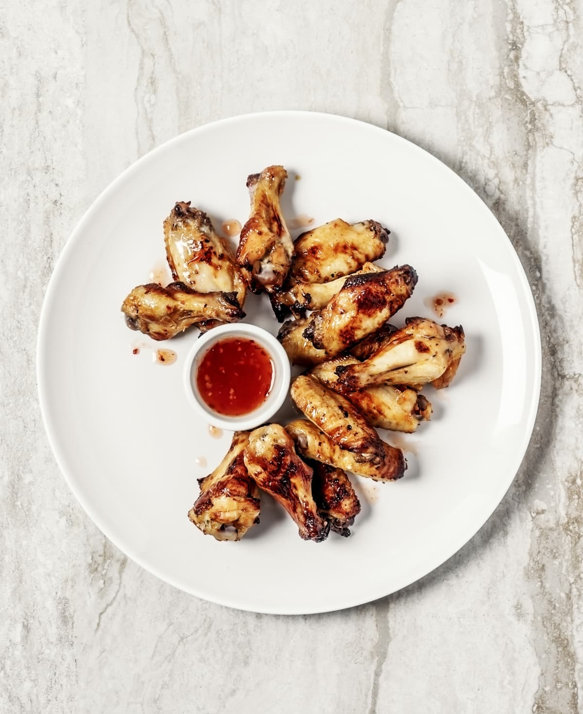 A plate of roasted chicken wings with dipping sauce