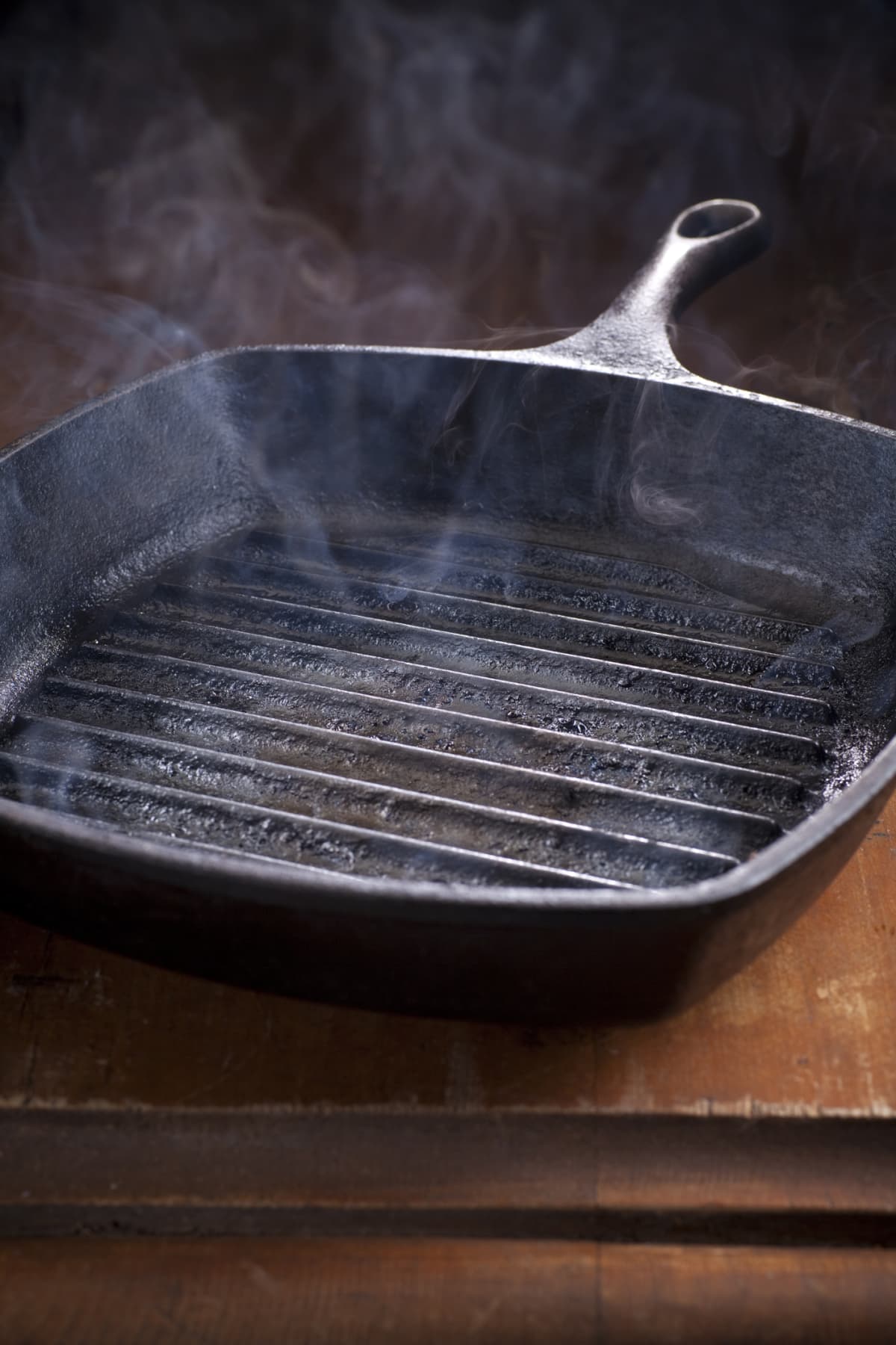 Smoking cast iron griddle pan on a dark wooden table, Newport, Wales, 2010