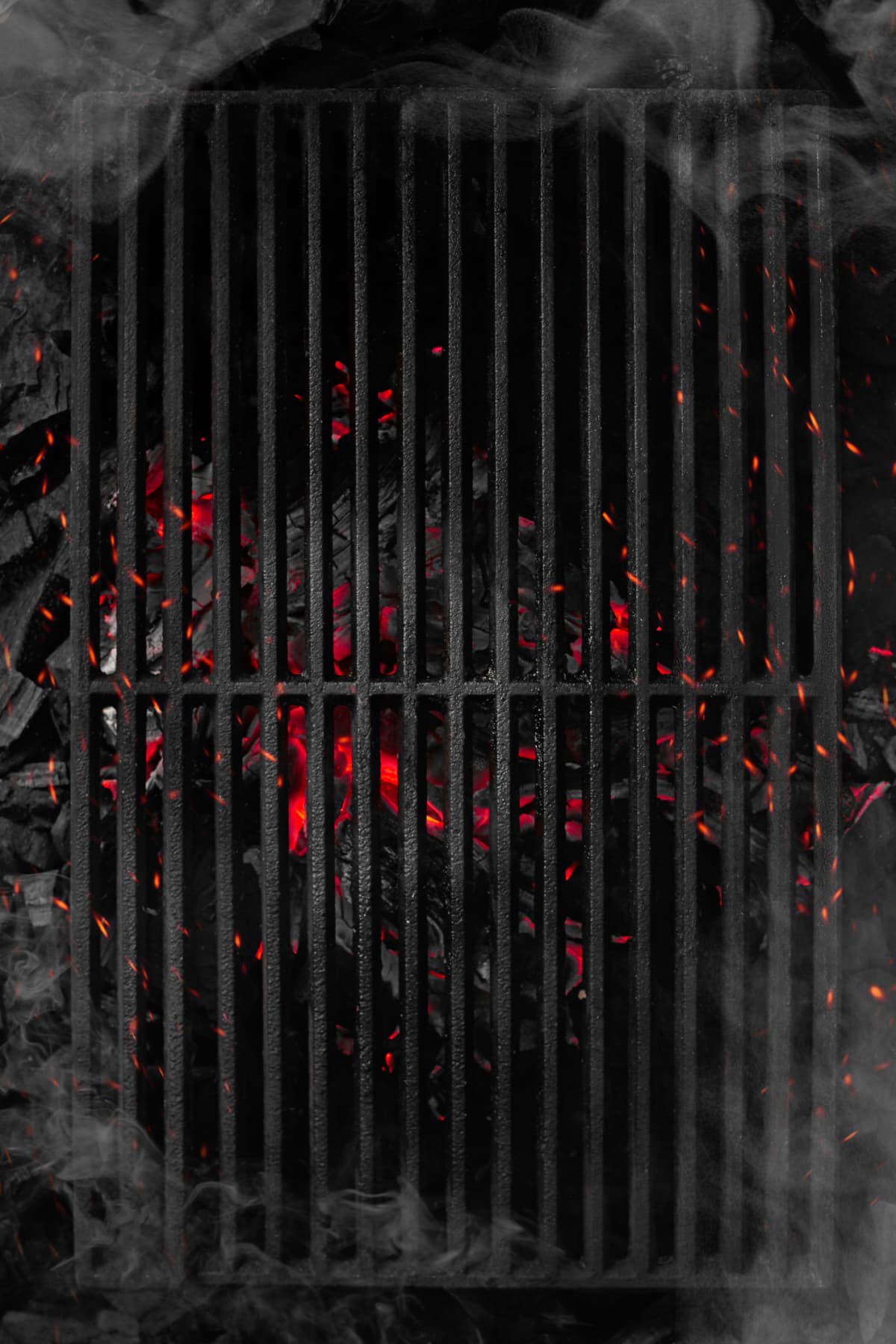 Smoldering charcoals under a grill grate