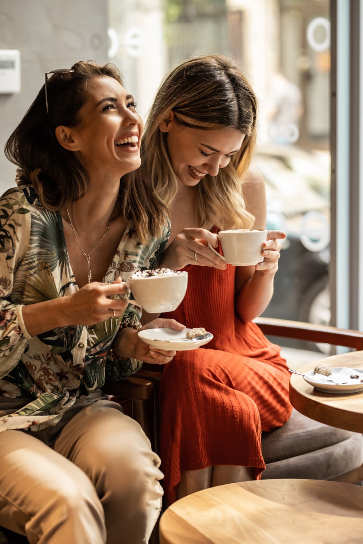High angle shot of two attractive young women using their cellphones while sitting in a local coffee shop