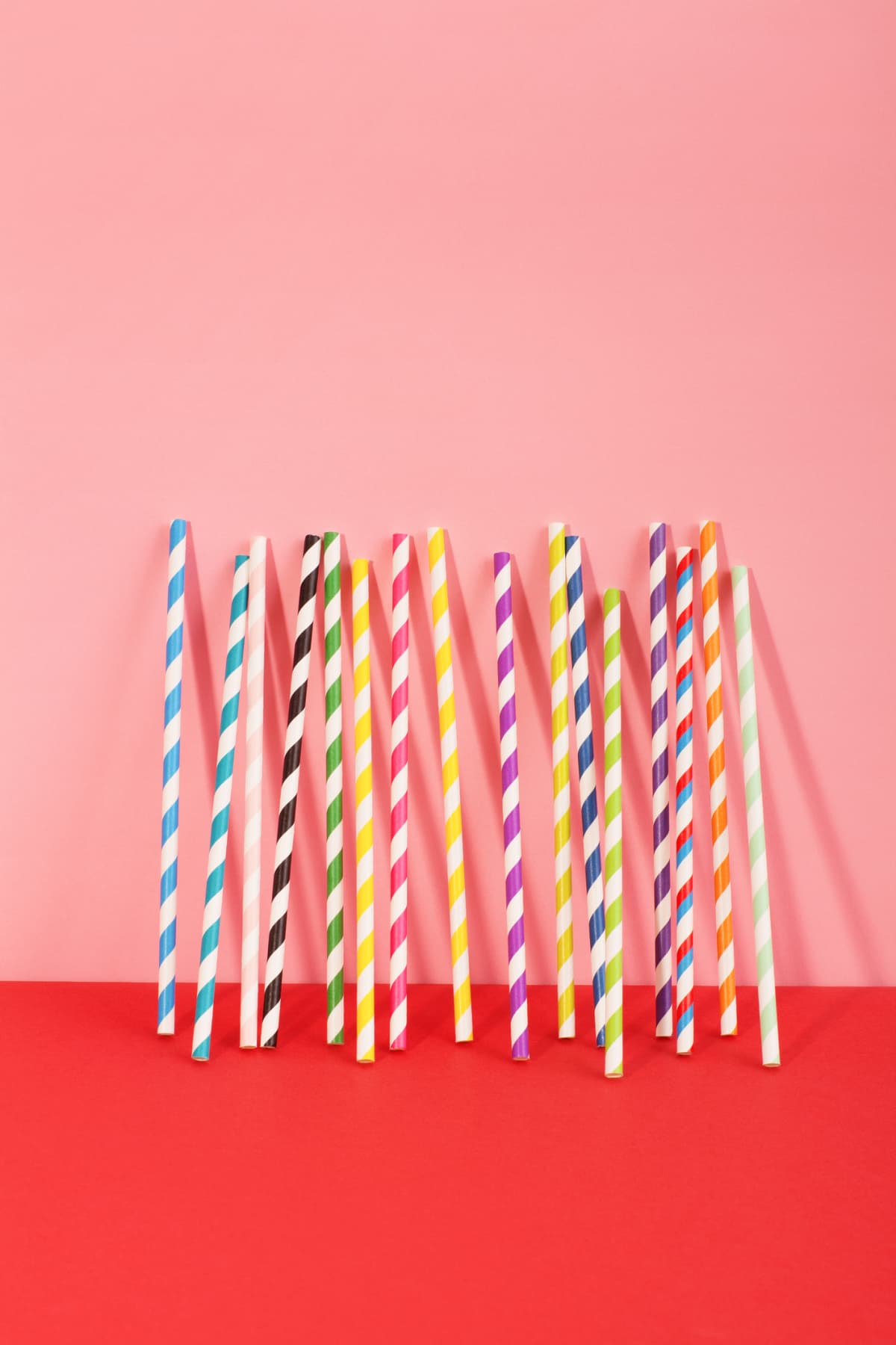 Still life of multicolour straws shot on pink and red background