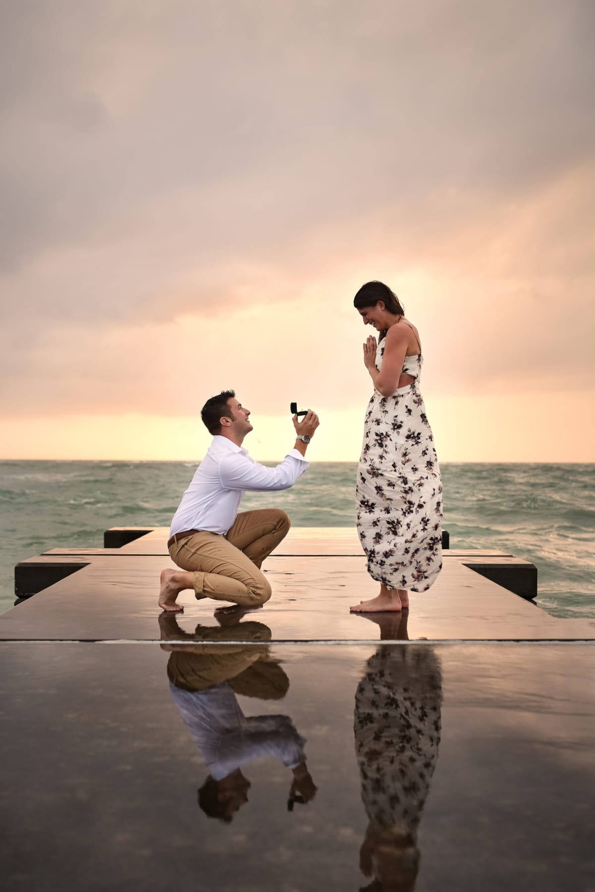 Full length shot of a handsome young man proposing to his girlfriend on the jetty at the beach