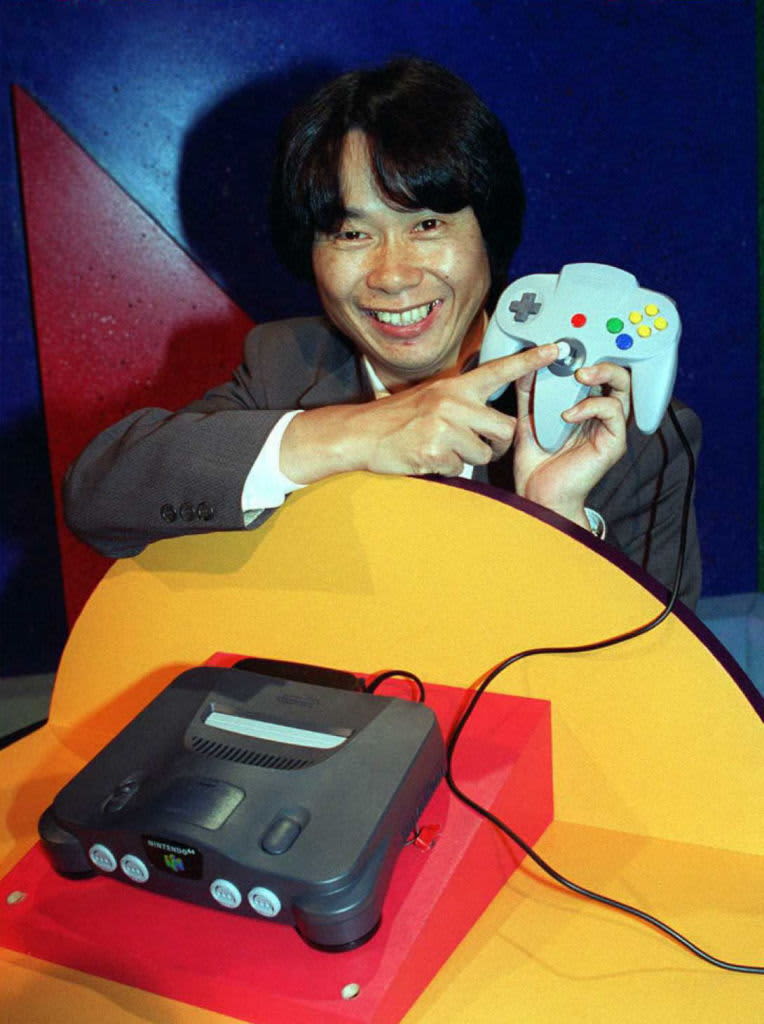 Video game designer, Shigeru Miyamoto from Japan, points to the handset of the new Nintendo 64 flagship game, Super Mario 64, at the Los Angeles Electronic Entertainment Expo 15 May.  The world's first true 64-bit video game system will produce three-dimensional environments and is equal to the power of ten Pentium chips bundled together making it the most powerful video game. 
            AFP PHOTO    John T. BARR/mn (Photo by JOHN T. BARR / AFP) (Photo by JOHN T. BARR/AFP via Getty Images)