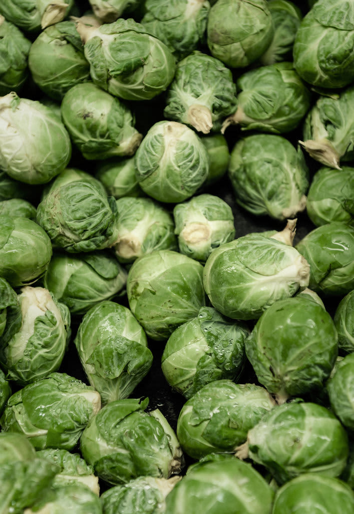 Bowl of whole baked brussel sprouts on blue tablecloth. Vegan dish. Flat lay, copy space. (Photo by: Natasha Breen/REDA&CO/Universal Images Group via Getty Images)