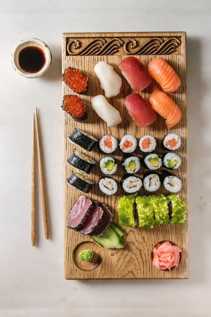 Sushi Set nigiri sashimi and sushi rolls on wooden serving board with soy sauce and chopsticks over grey concrete background. Flat lay. space. Japan menu. (Photo by: Natasha Breen/REDA&CO/Universal Images Group via Getty Images)