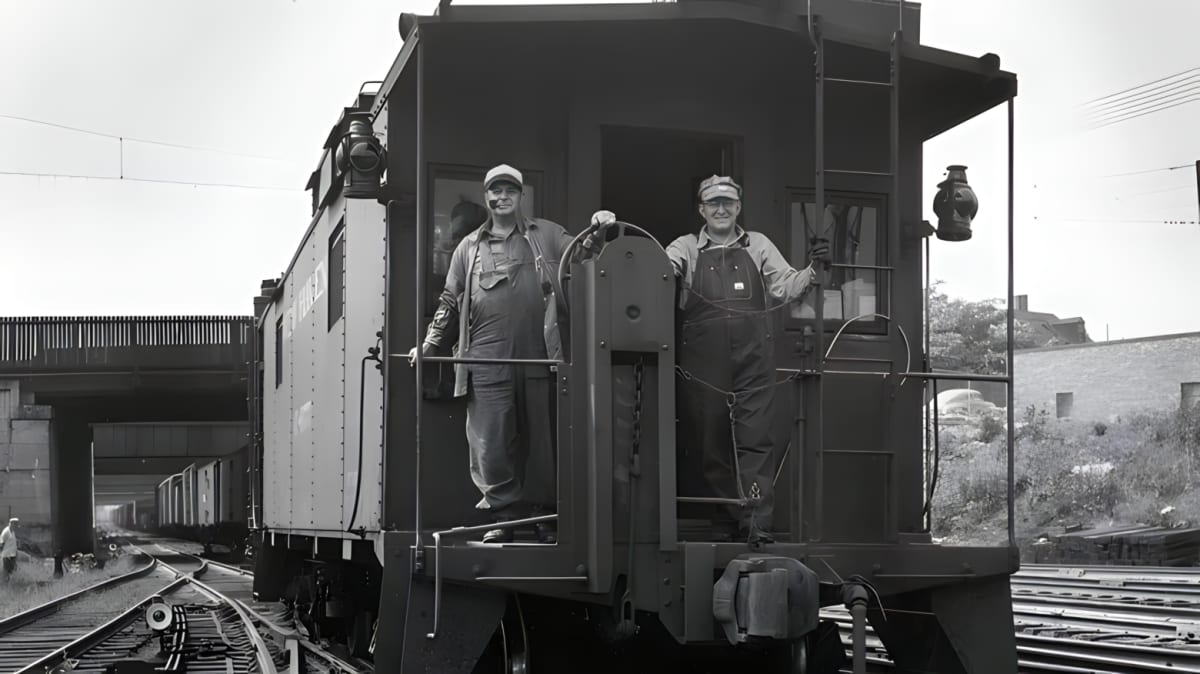 An old photo of a railway worker riding in the caboose of a train 