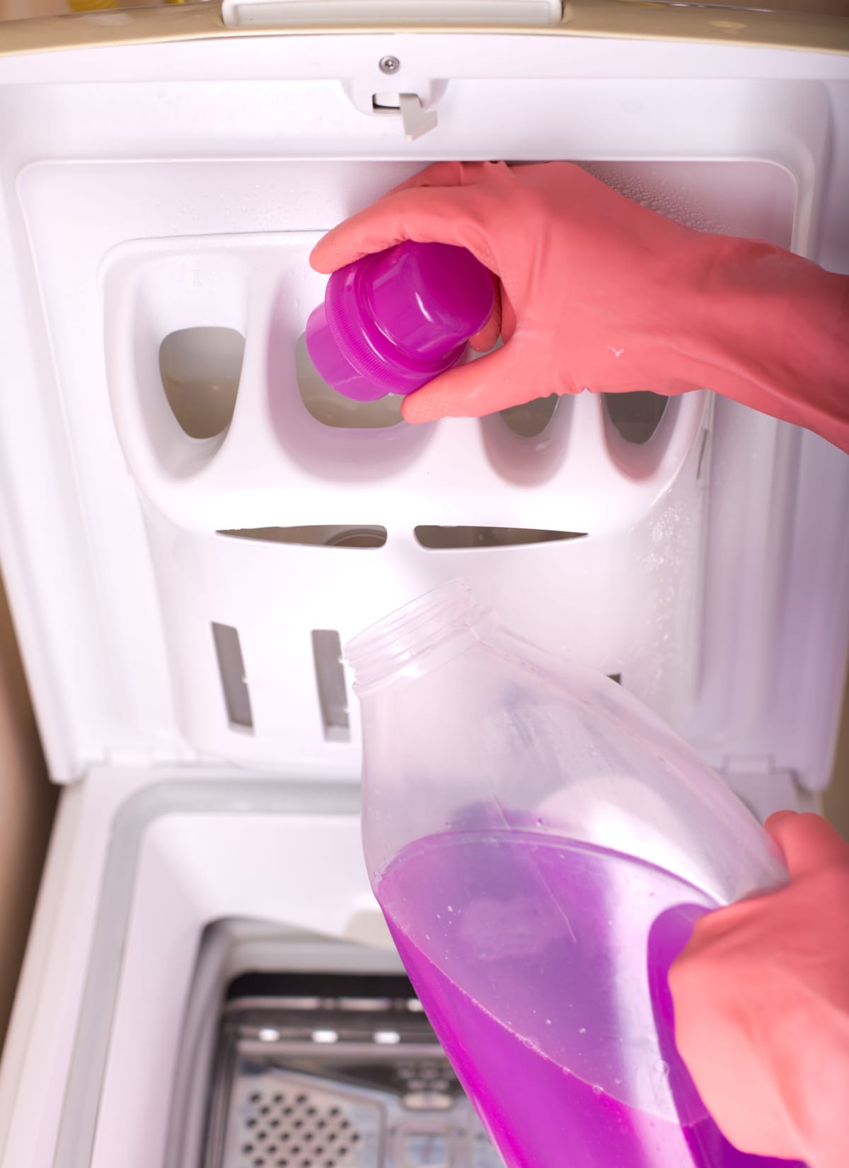 A person pouring detergent in a top-loading washing machine