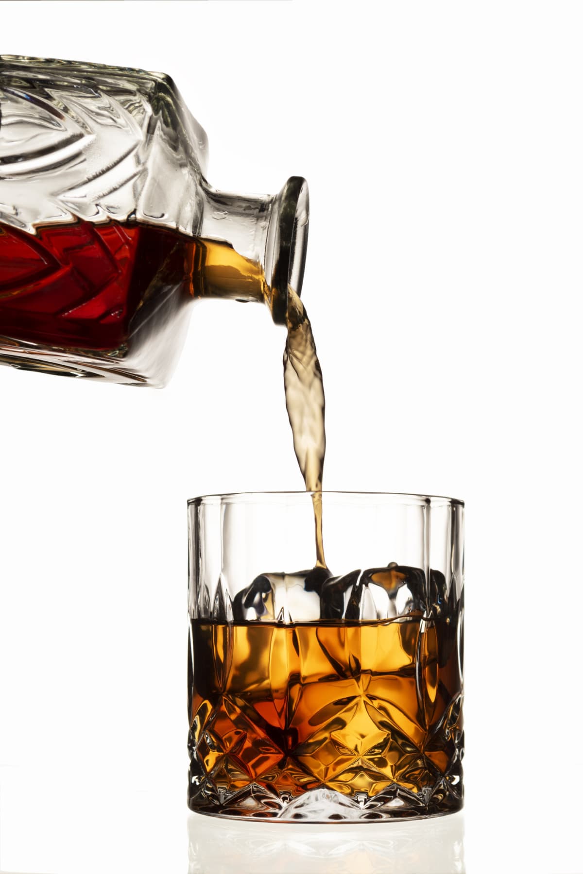 bourbon being poured into a rocks glass from a decanter