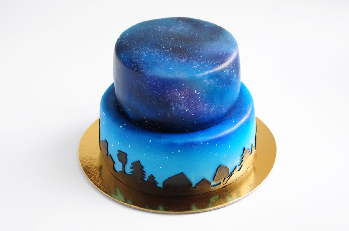 A two tiered galaxy cake with fondant embellishments