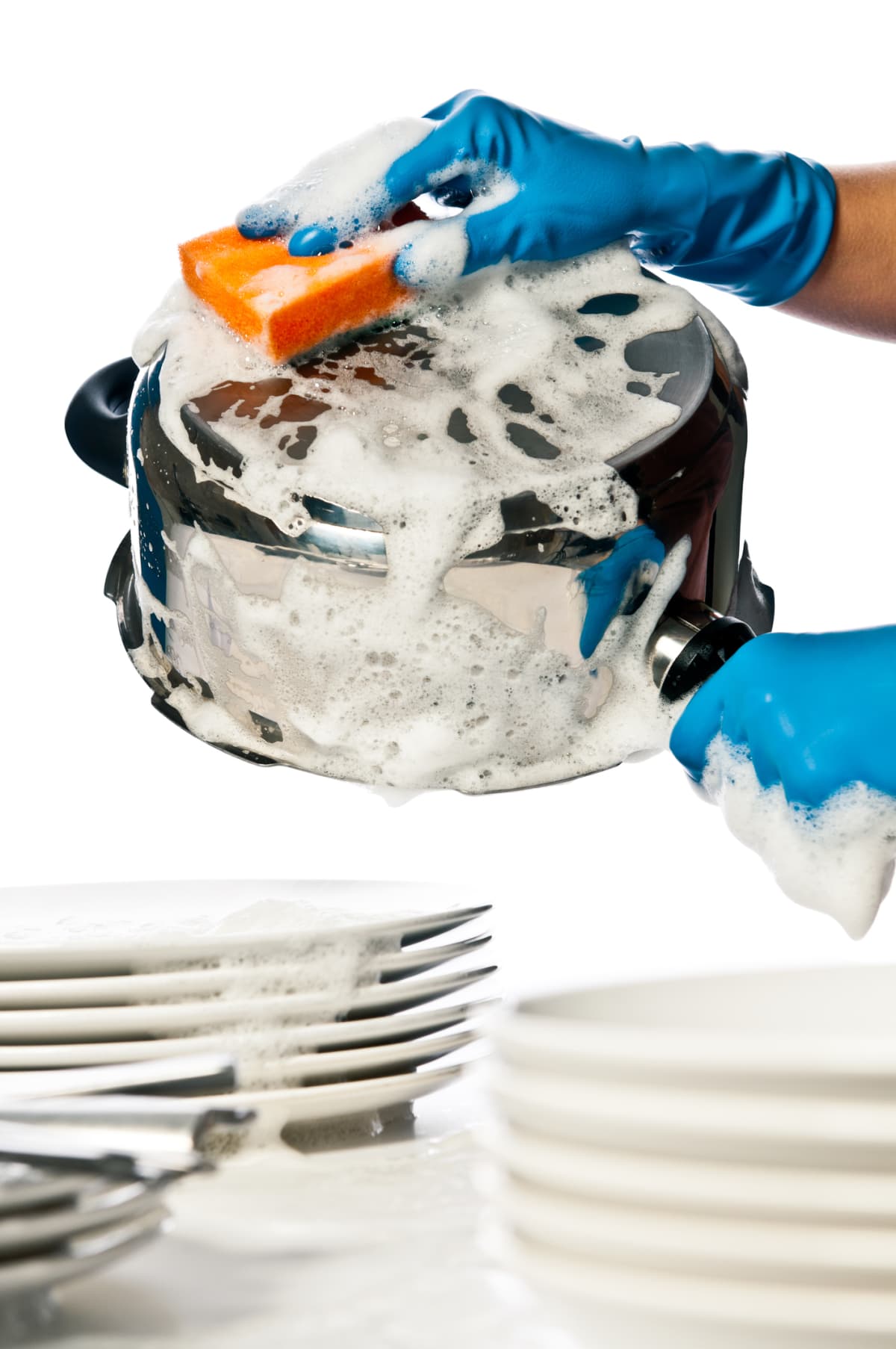 Close-up of woman's hands in protective gloves washing dishes and pots in the kitchen, isolated on white background, studio shot.