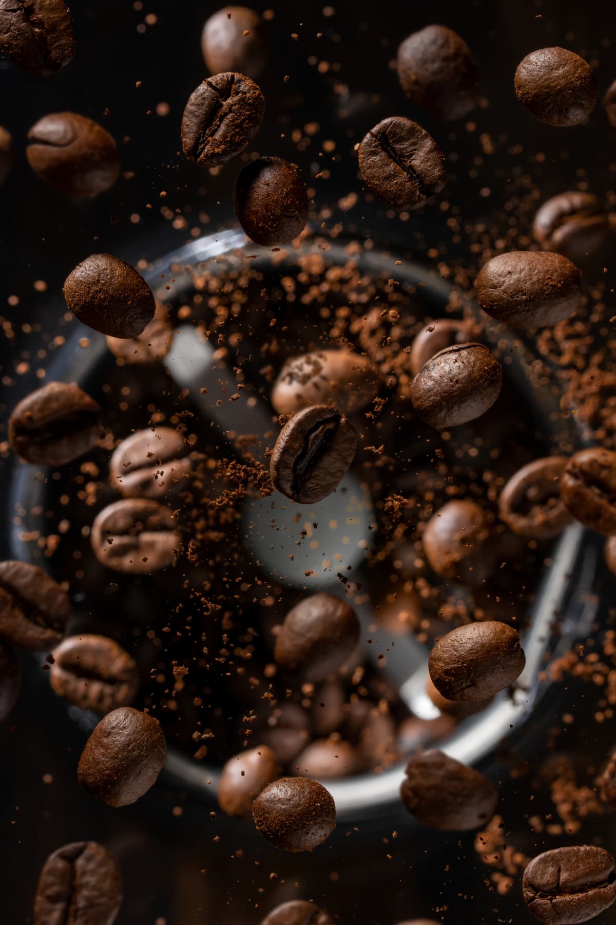 Close-up of falling steaming coffee beans. Selective focus. The concept of coffee roasting, high-quality products. Vertical view