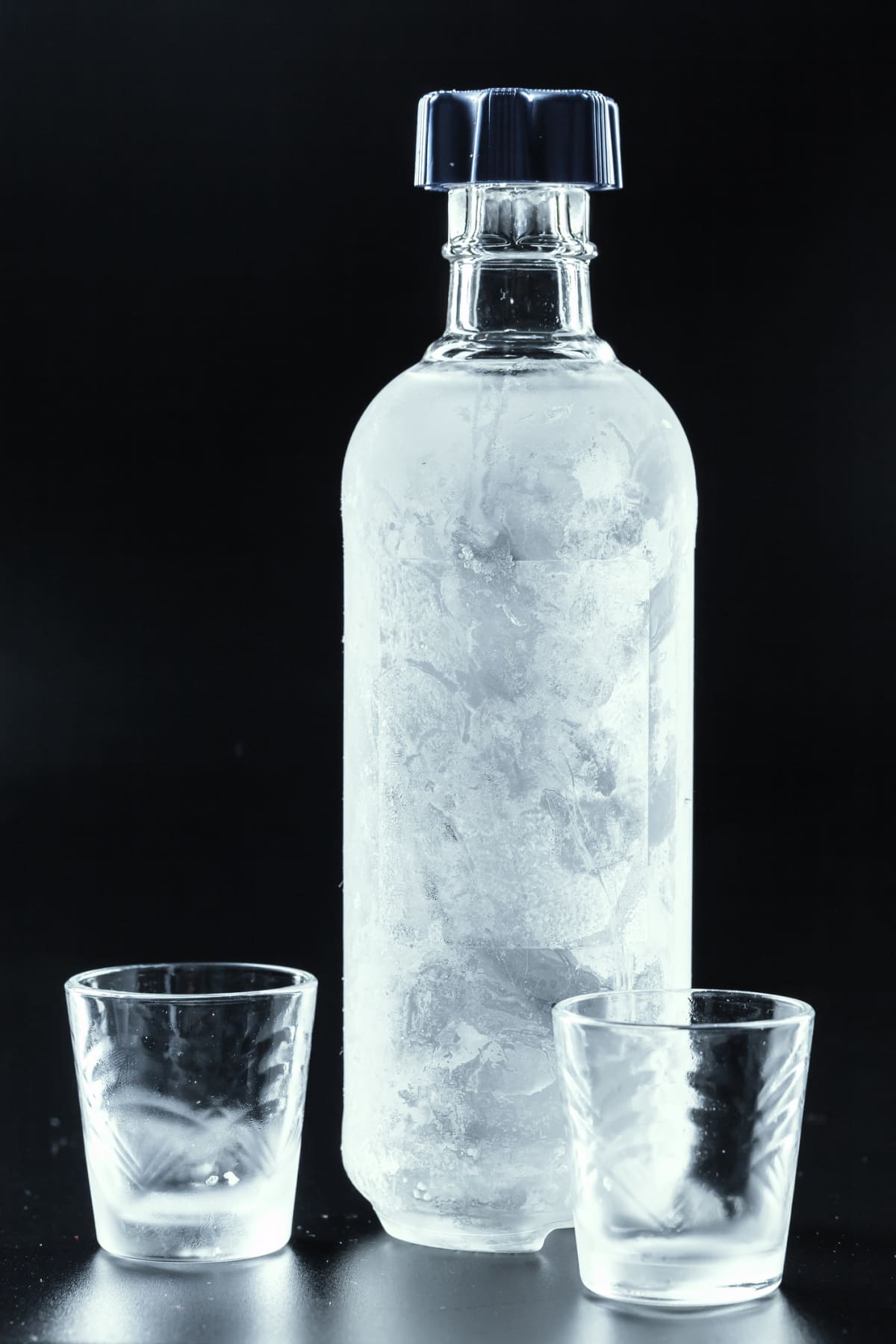 Bottle of cold vodka on dark background