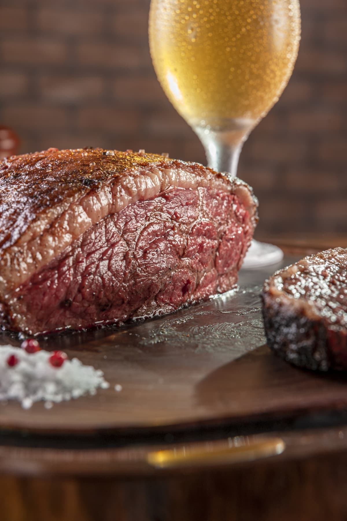 Closeup of steak next to glass of beer