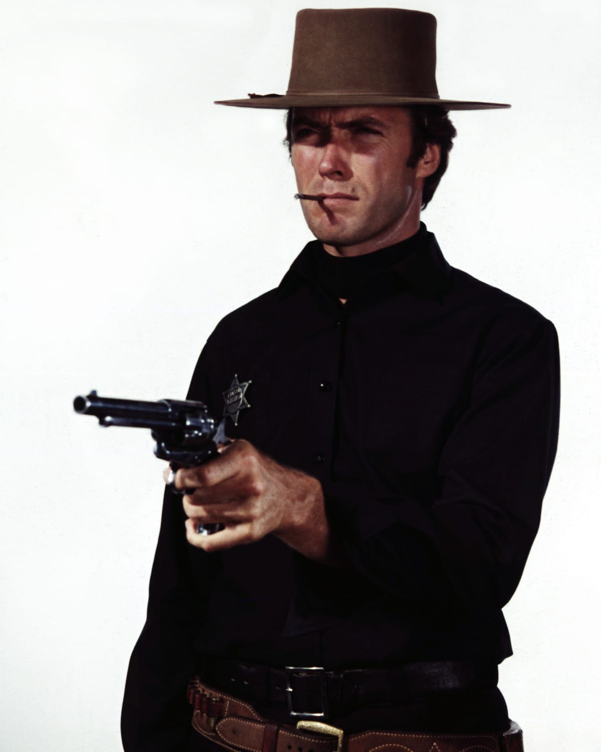 Clint Eastwood in Western attire, smoking a cigar and pointing a gun