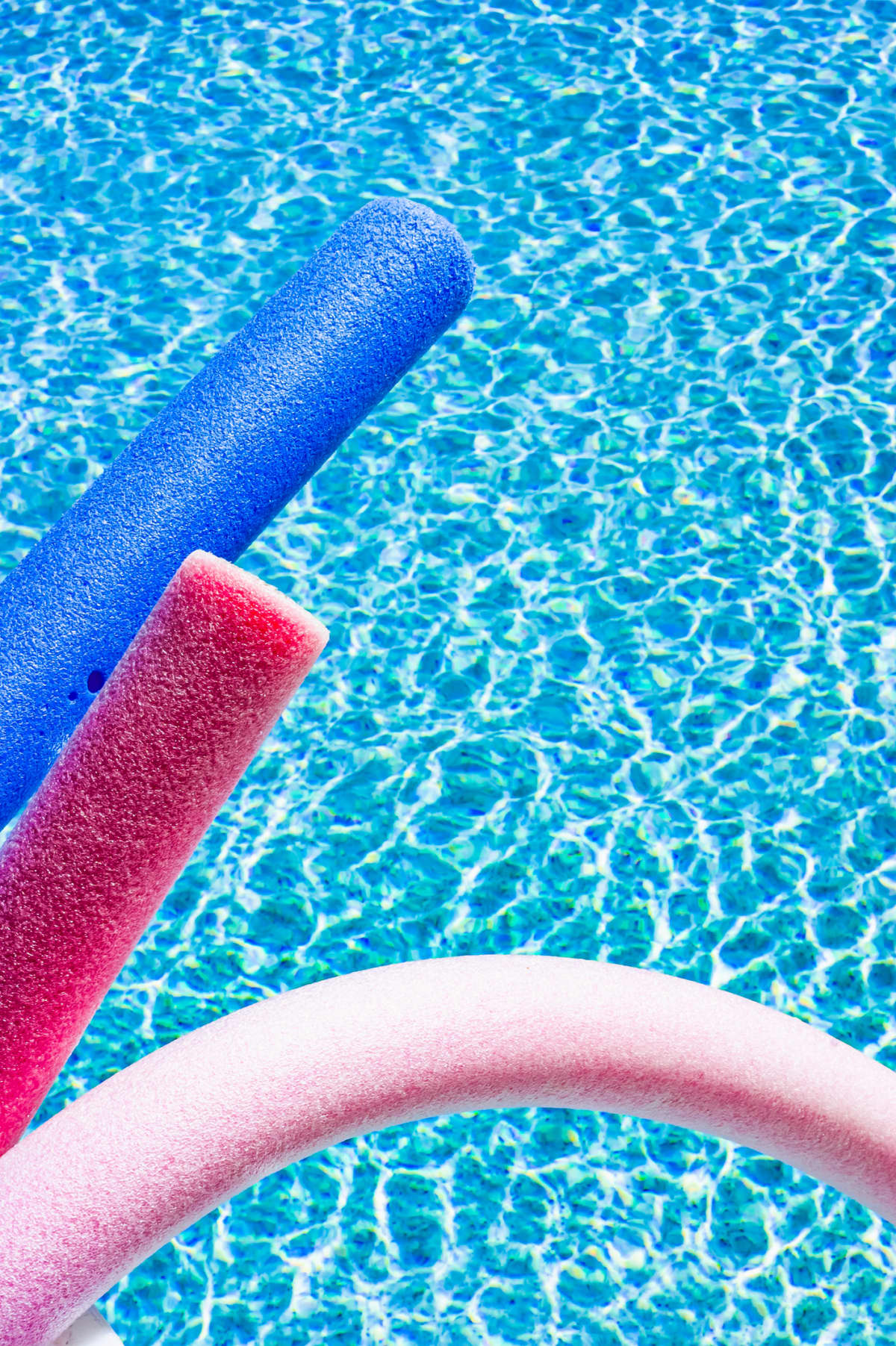 Brightly colored foam pool noodles dangling over pool