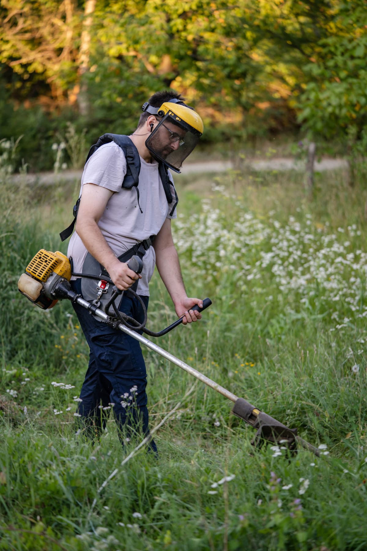 Man trims grass with power tool