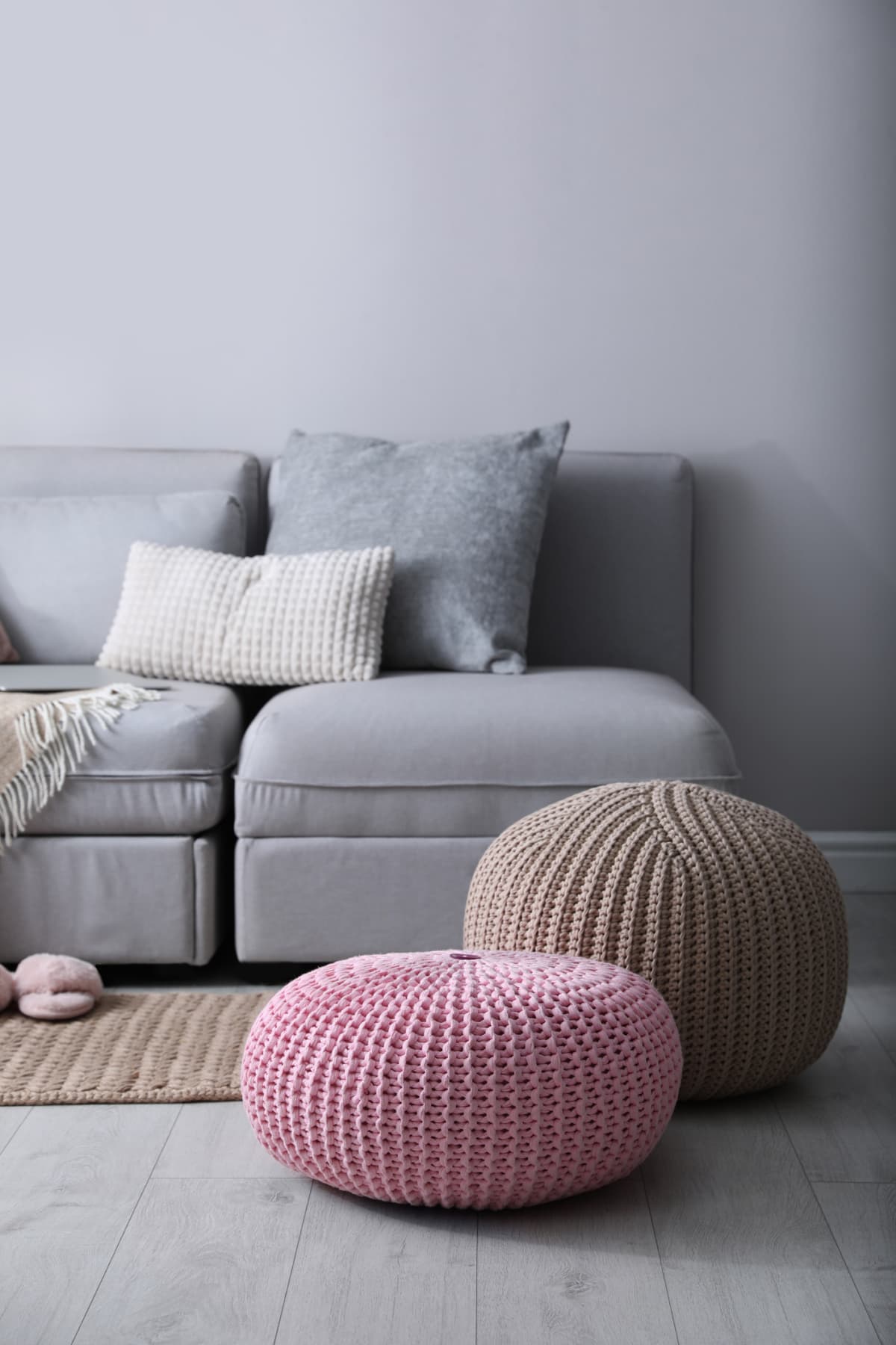 Stylish knitted poufs in front of gray living room sofa