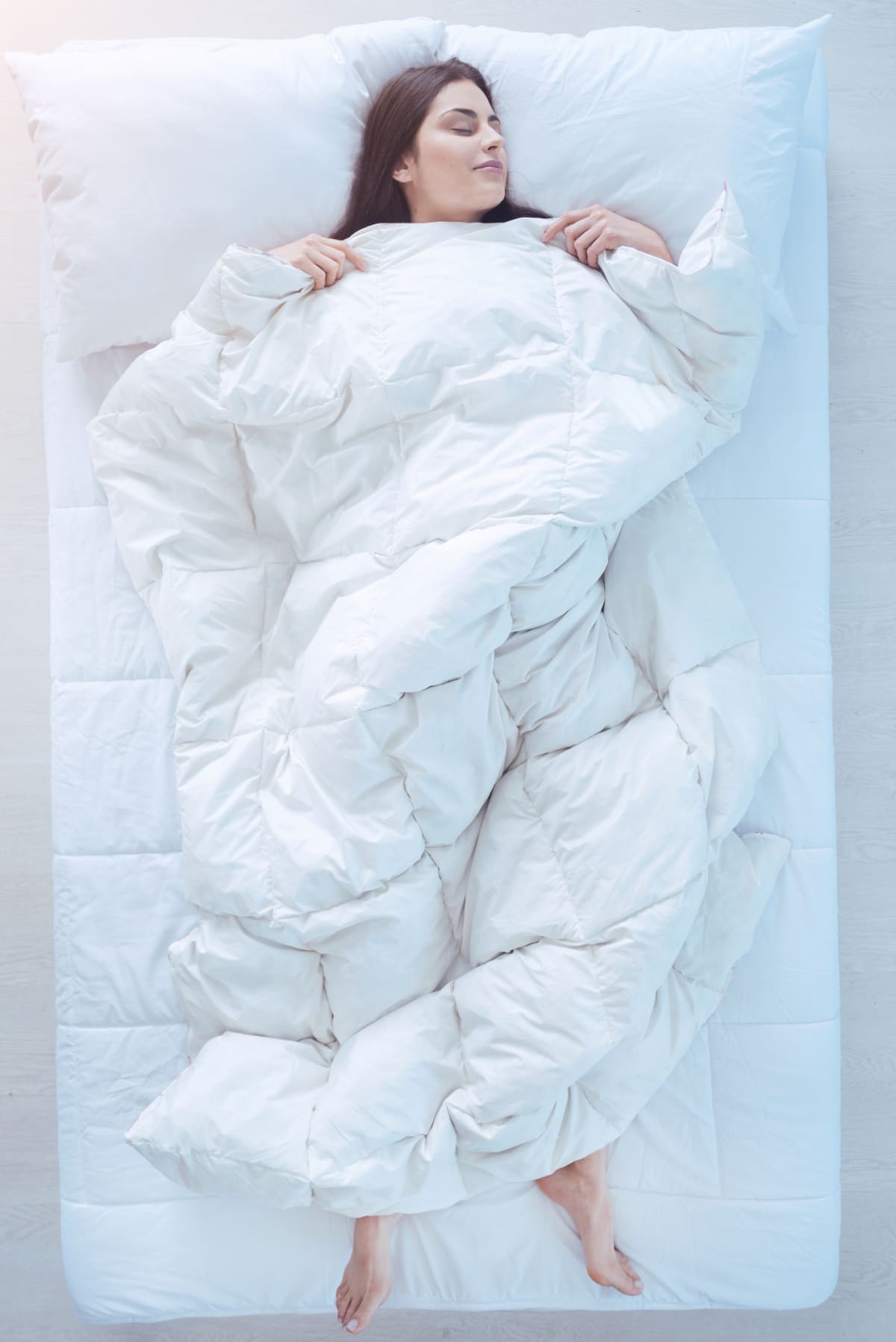 A woman sleeping peacefully while covered in a duvet