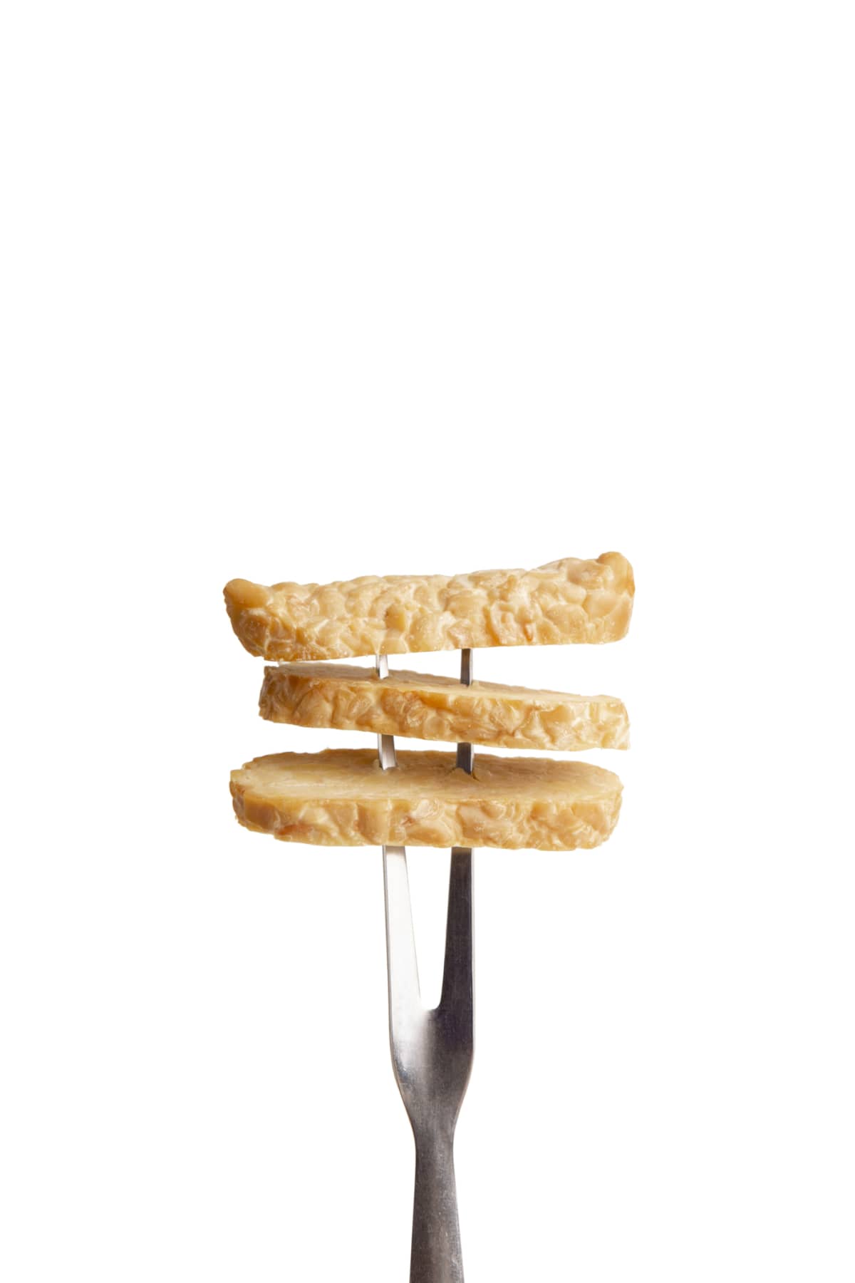 Three slices of tempeh on a fork