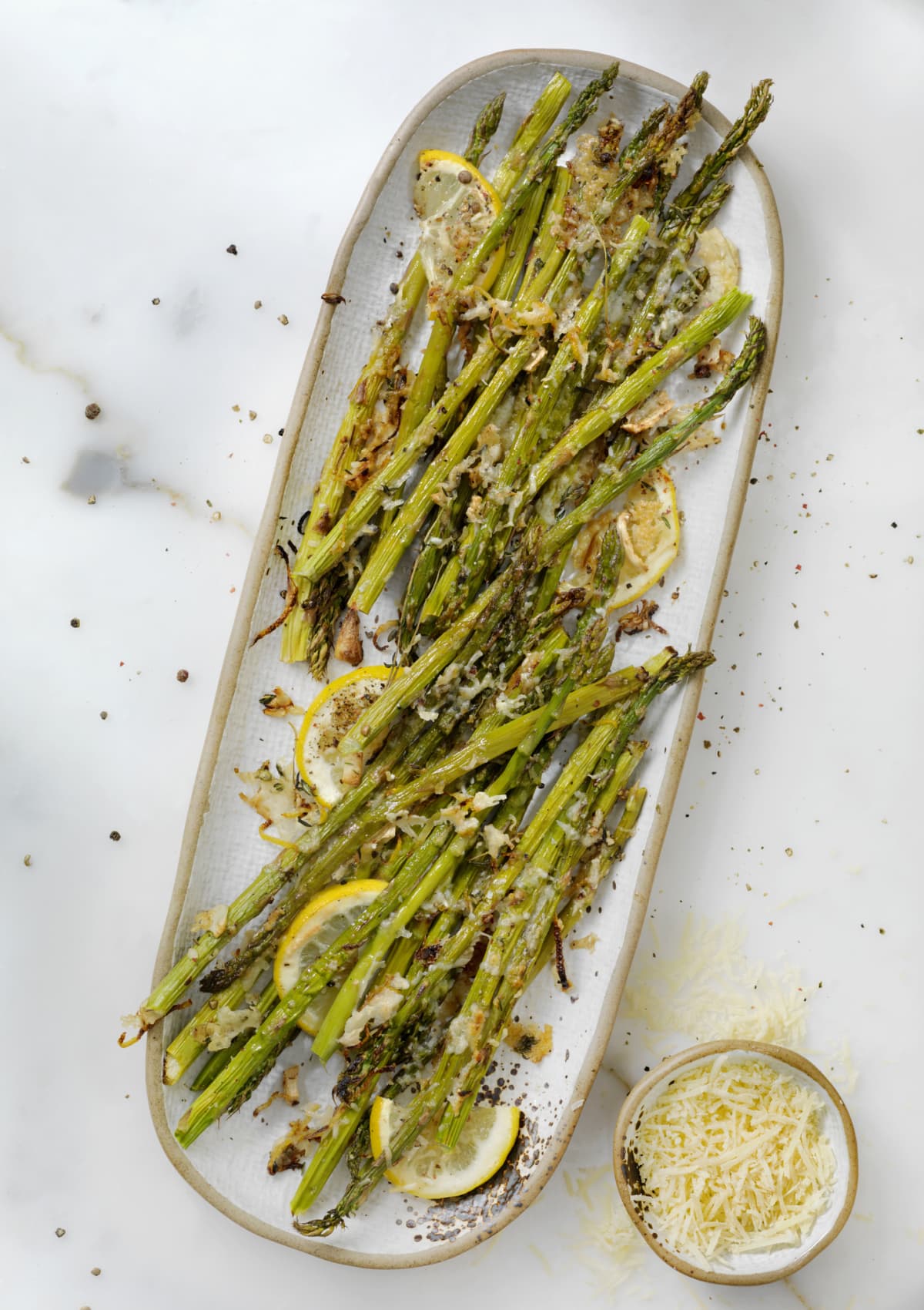 Lemon, garlic, and parmesan roasted asparagus on a white tray