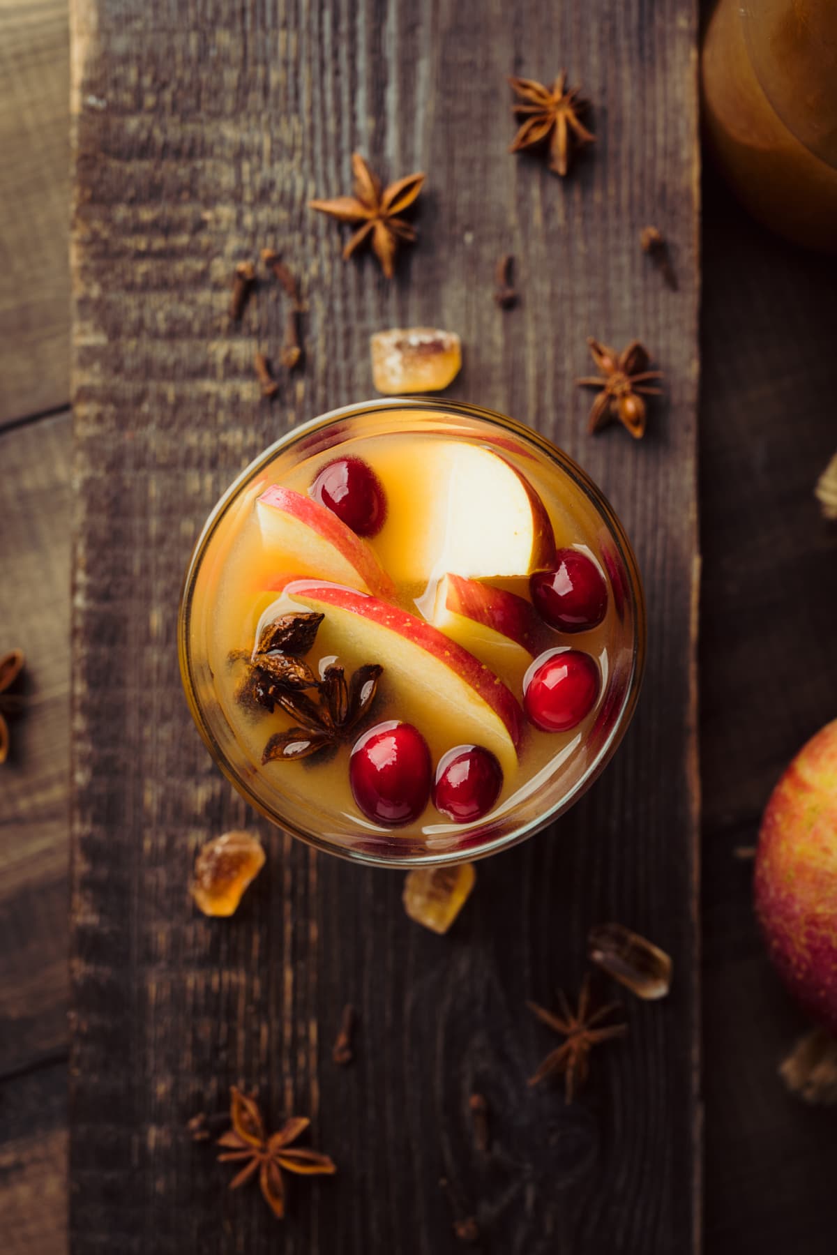 Glass of apple cider topped with cranberries, apple slices, and star of anise