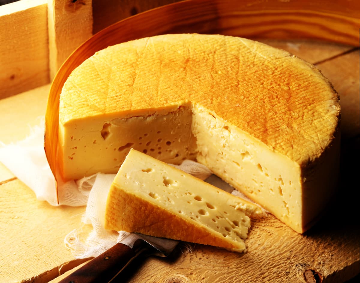 Close up of a round of Stinking Bishop cheese with a large slice cut out