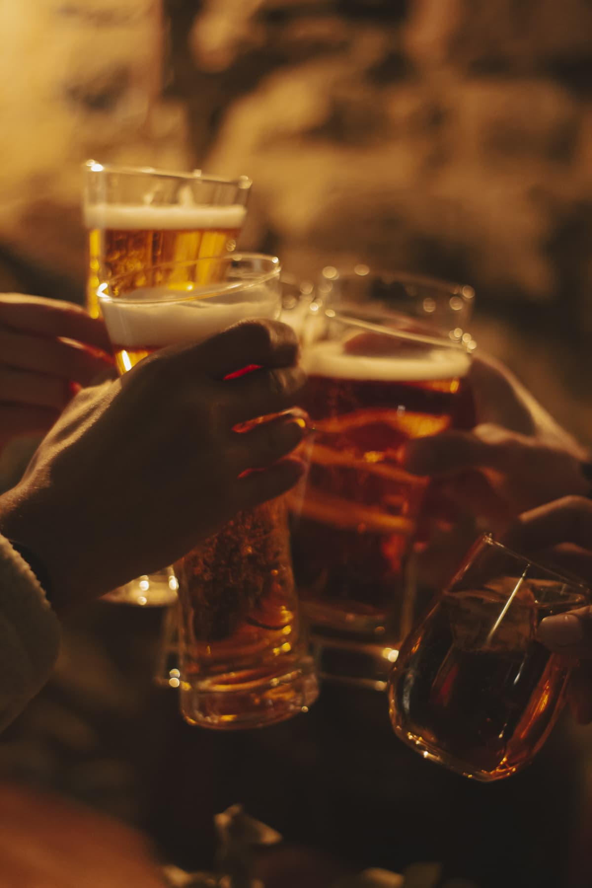 Multiple hands clinking beer glasses together