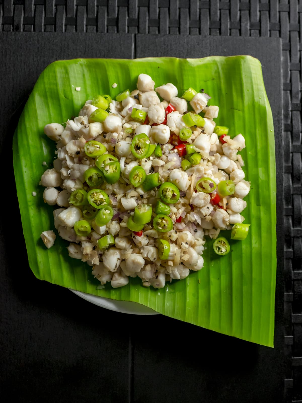 Top view of Scallop Ceviche , also known as Kinilaw na Scallops. Chopped and mixed with chilies. On a plate covered with a banana leaf.