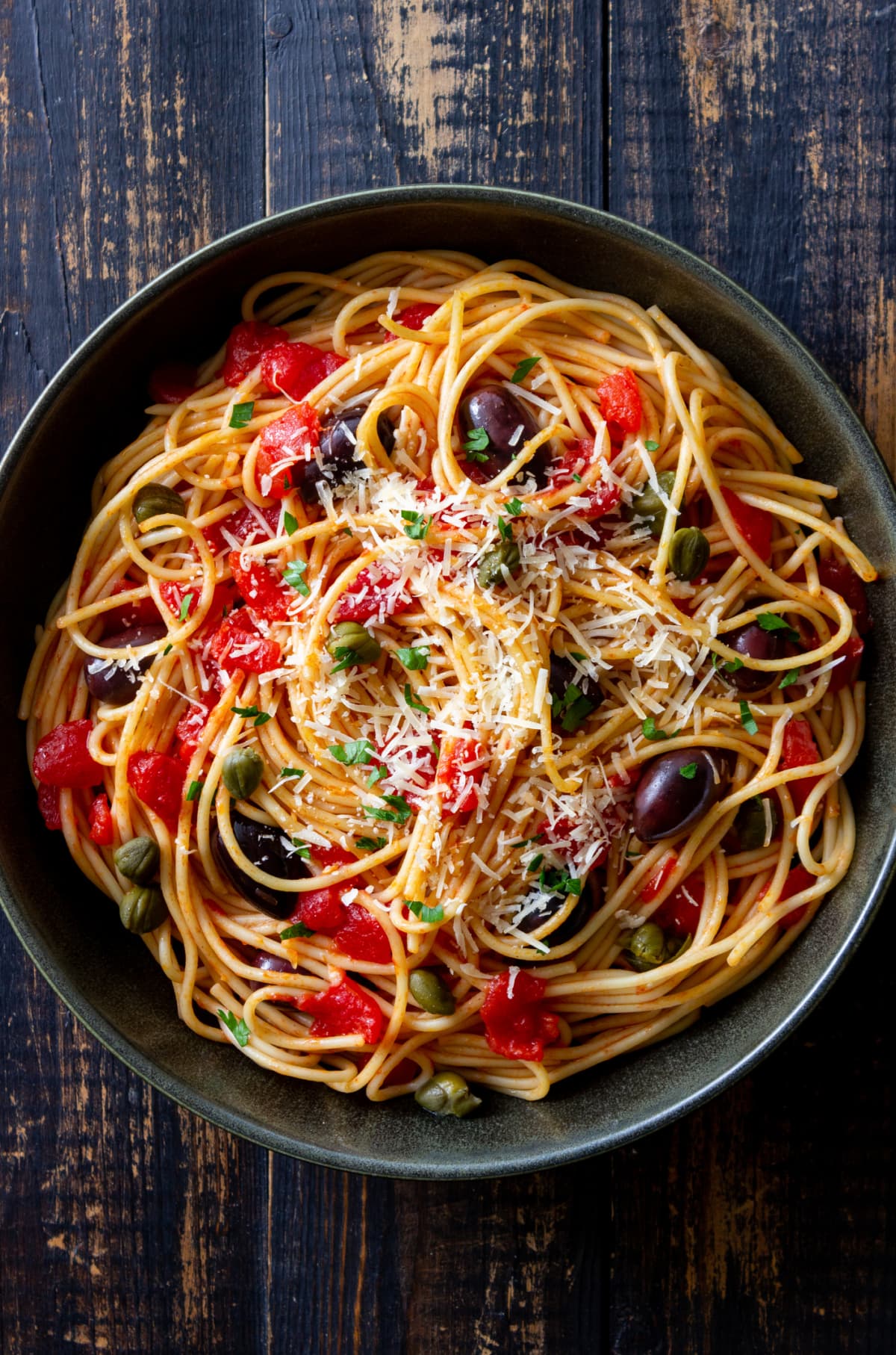 Spaghetti pasta Alla Puttanesca with capers, Kalamata olives, cheese, tomatoes and anchovies. Italian food