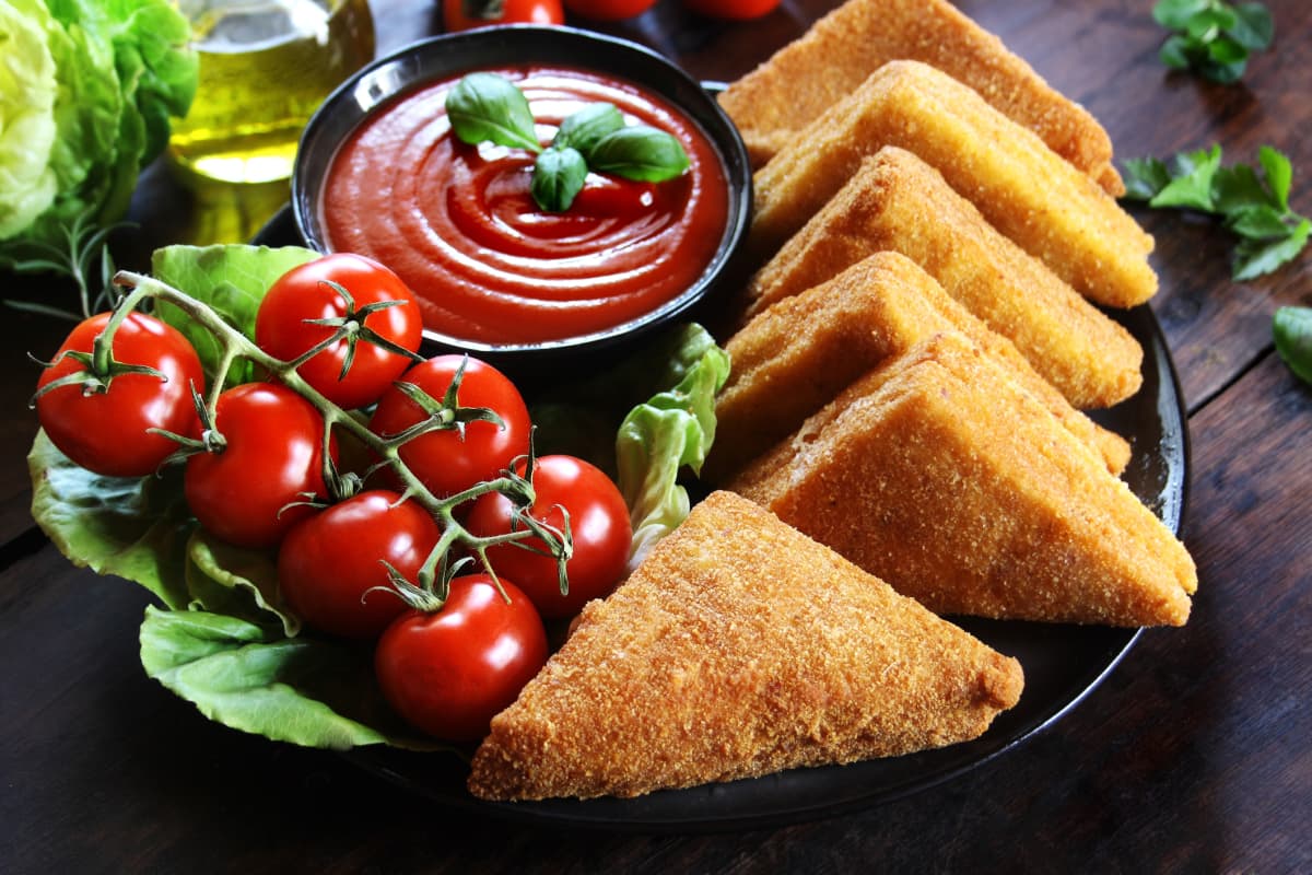 Close up of home-made mozzarella in carrozza, Italian fried mozzarella sandwiches on a plate ready to be deep fried.