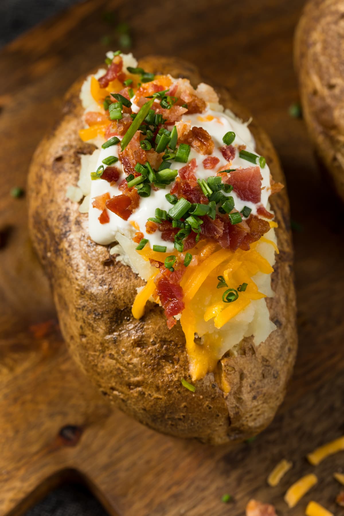 A baked potato with bacon, sour cream, and chives