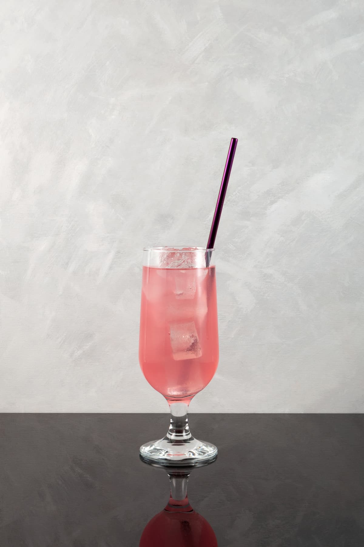Rose-flavored soda in a glass with ice and a straw