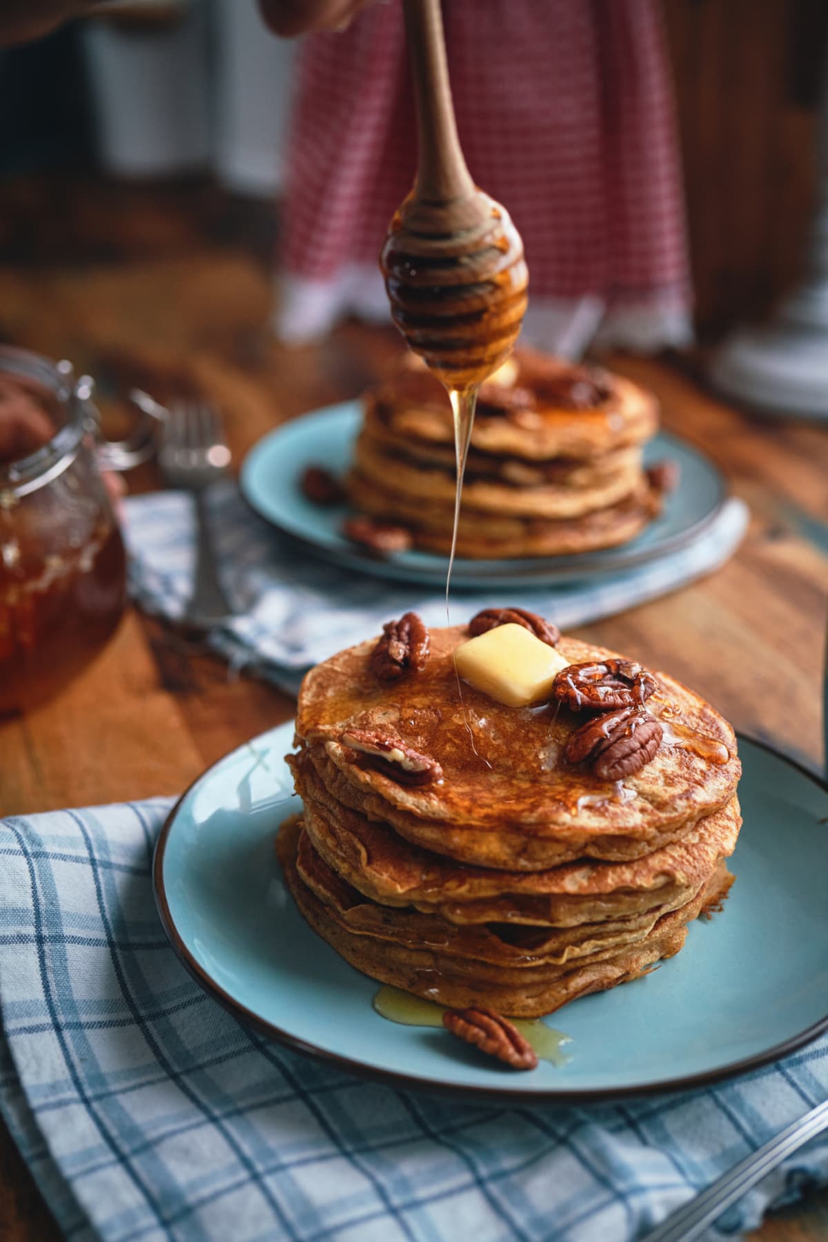 Stack of sweet potato pancakes with butter, pecans, and honey