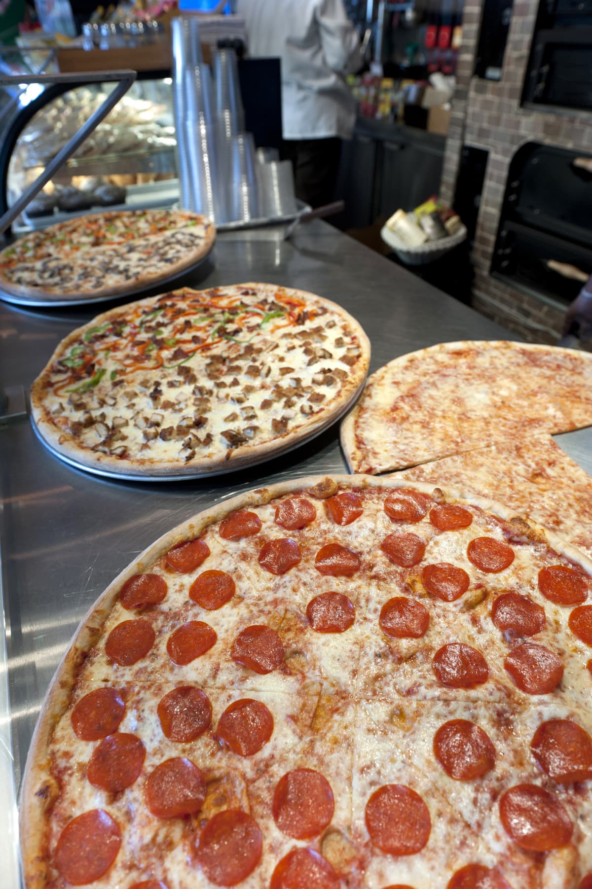 Large pizzas on a metal counter