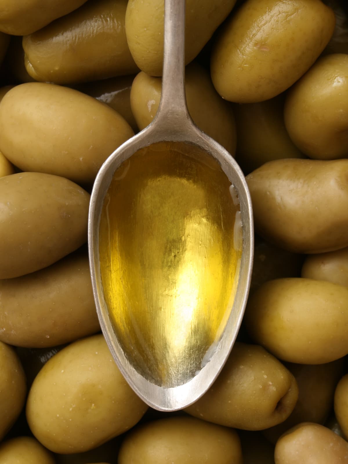 Spoon of olive oil on top of olives