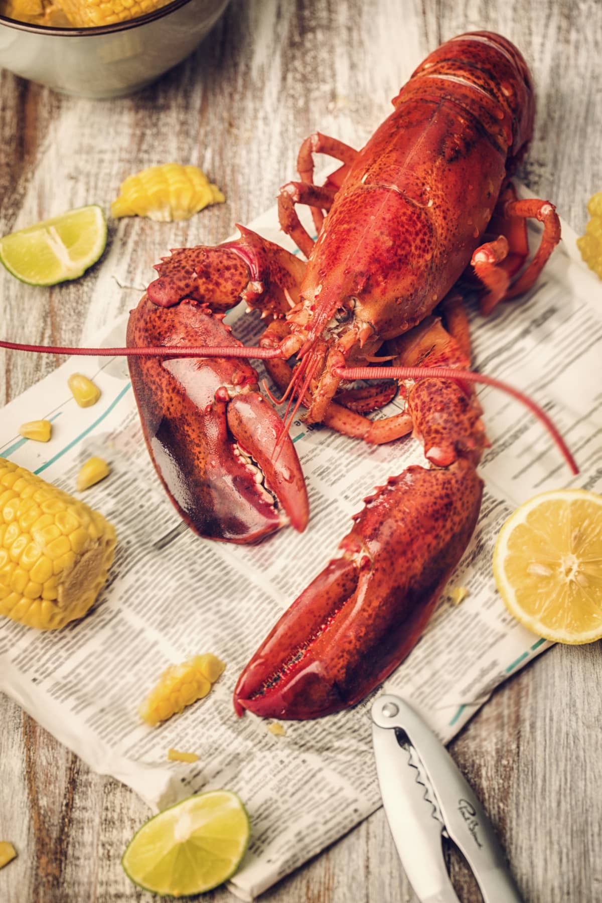 Whole lobster with lime wedges and corn