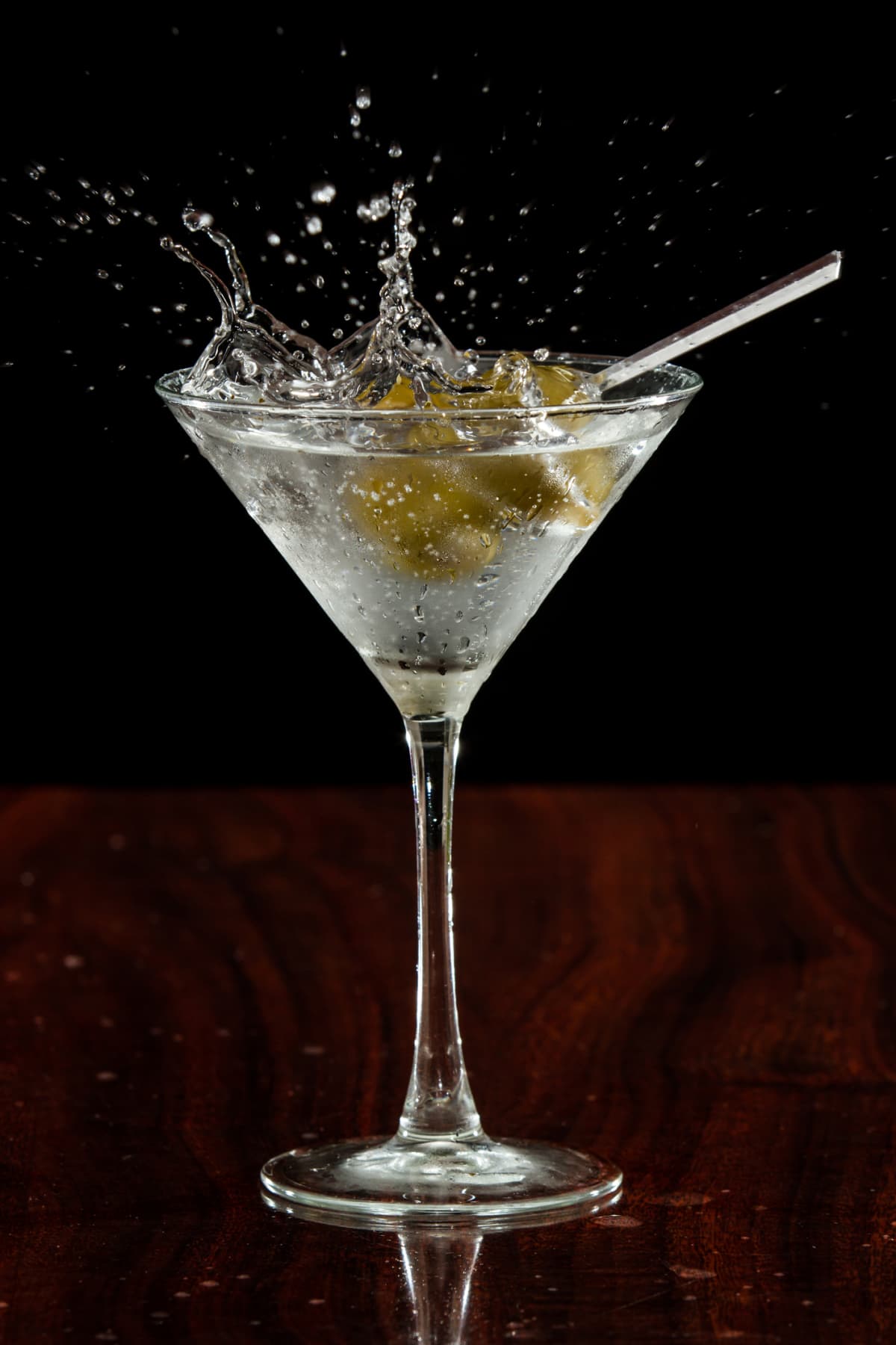 Dirty martini splashing on marble countertop with black background