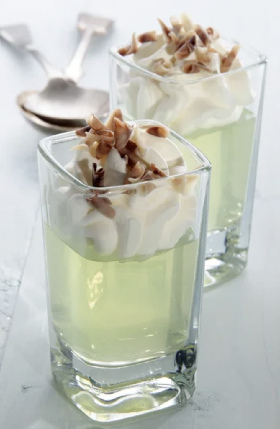 Two jello shots topped with whipped cream and chopped nuts