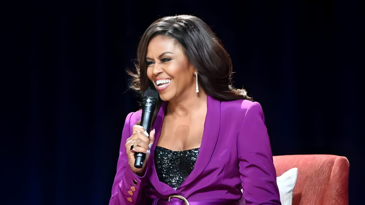 Michelle Obama smiling while holding a mic.