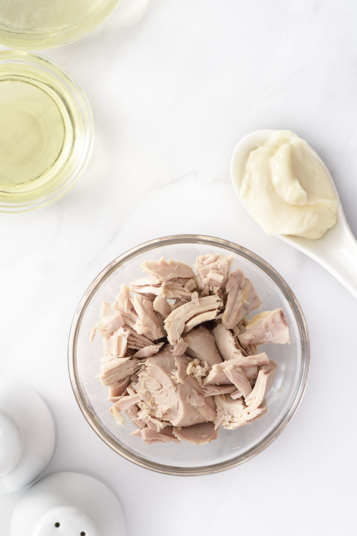 Preparing tuna salad with flaked tuna and mayonnaise on white background