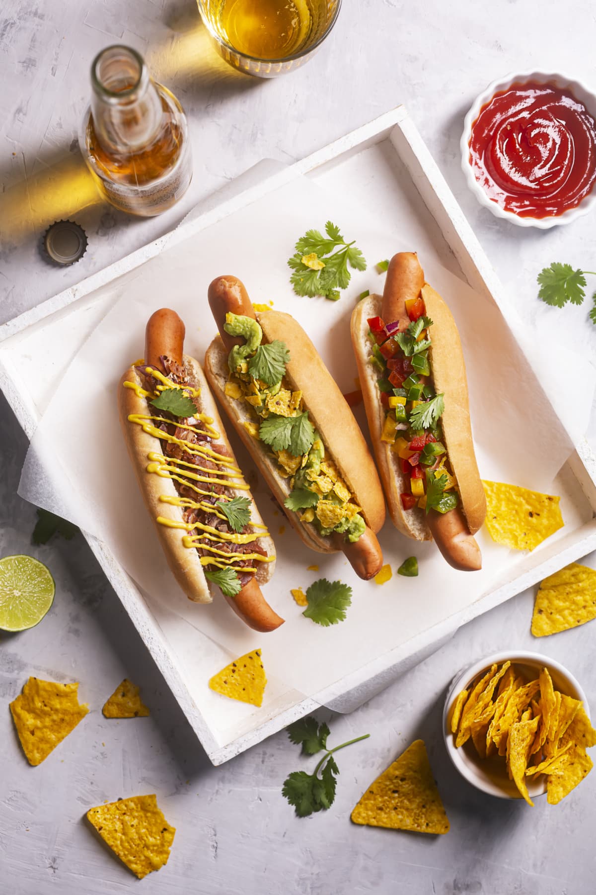 Hot dogs with different spicy toppings and mexican nachos, beer. Top view