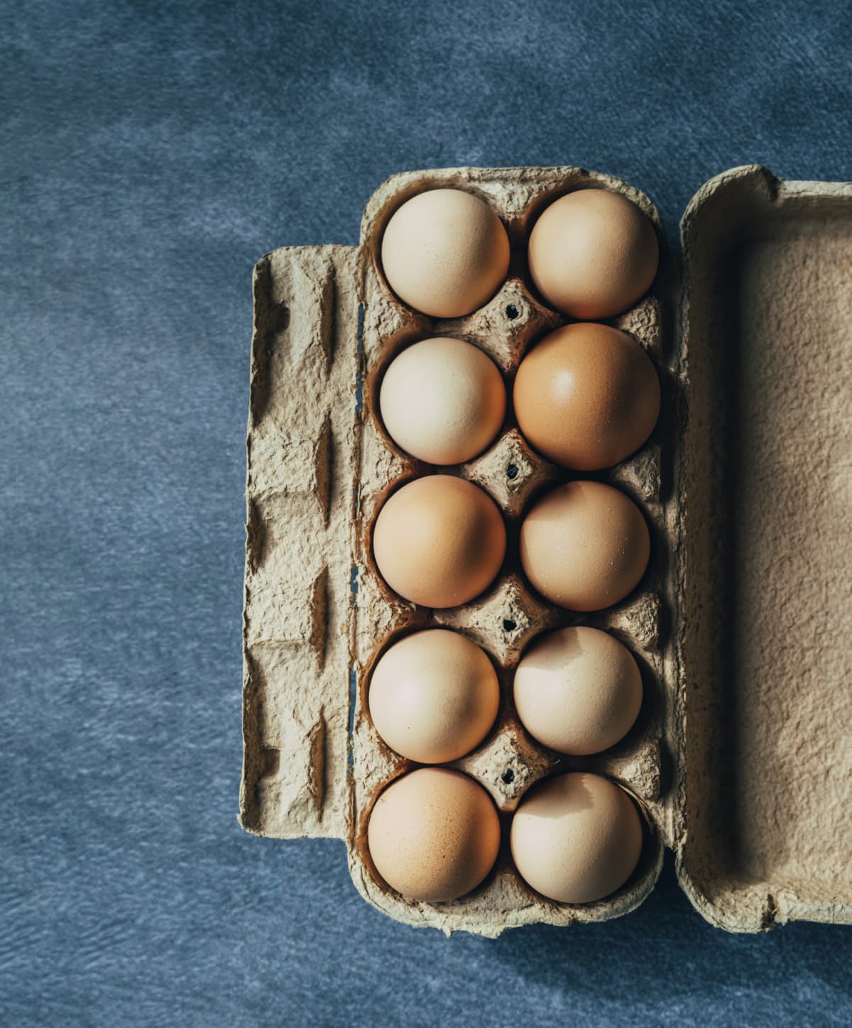 Directly above photo of dozen eggs on a blue table
