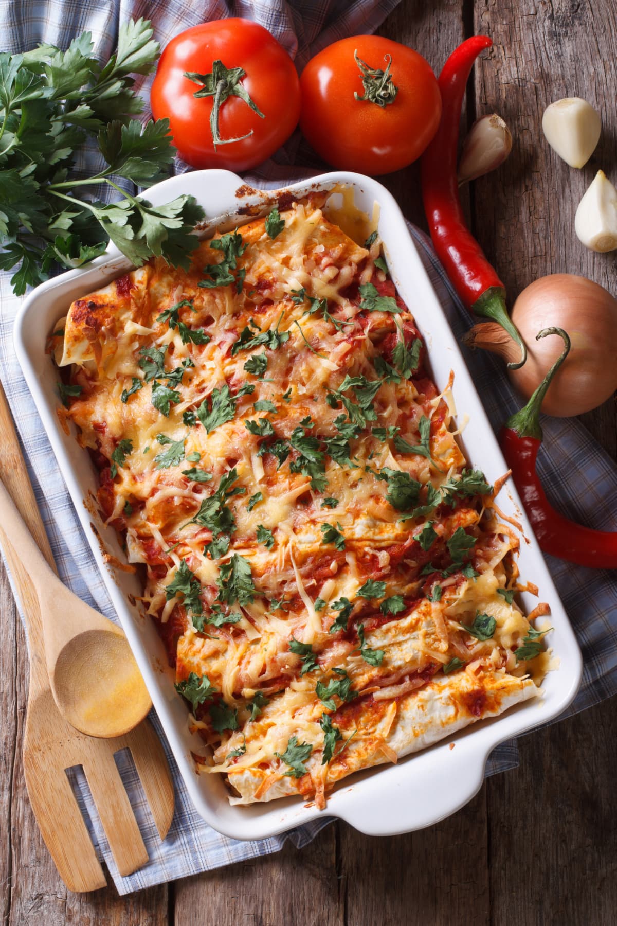 Casserole dish of enchiladas with red sauce topped with fresh herbs