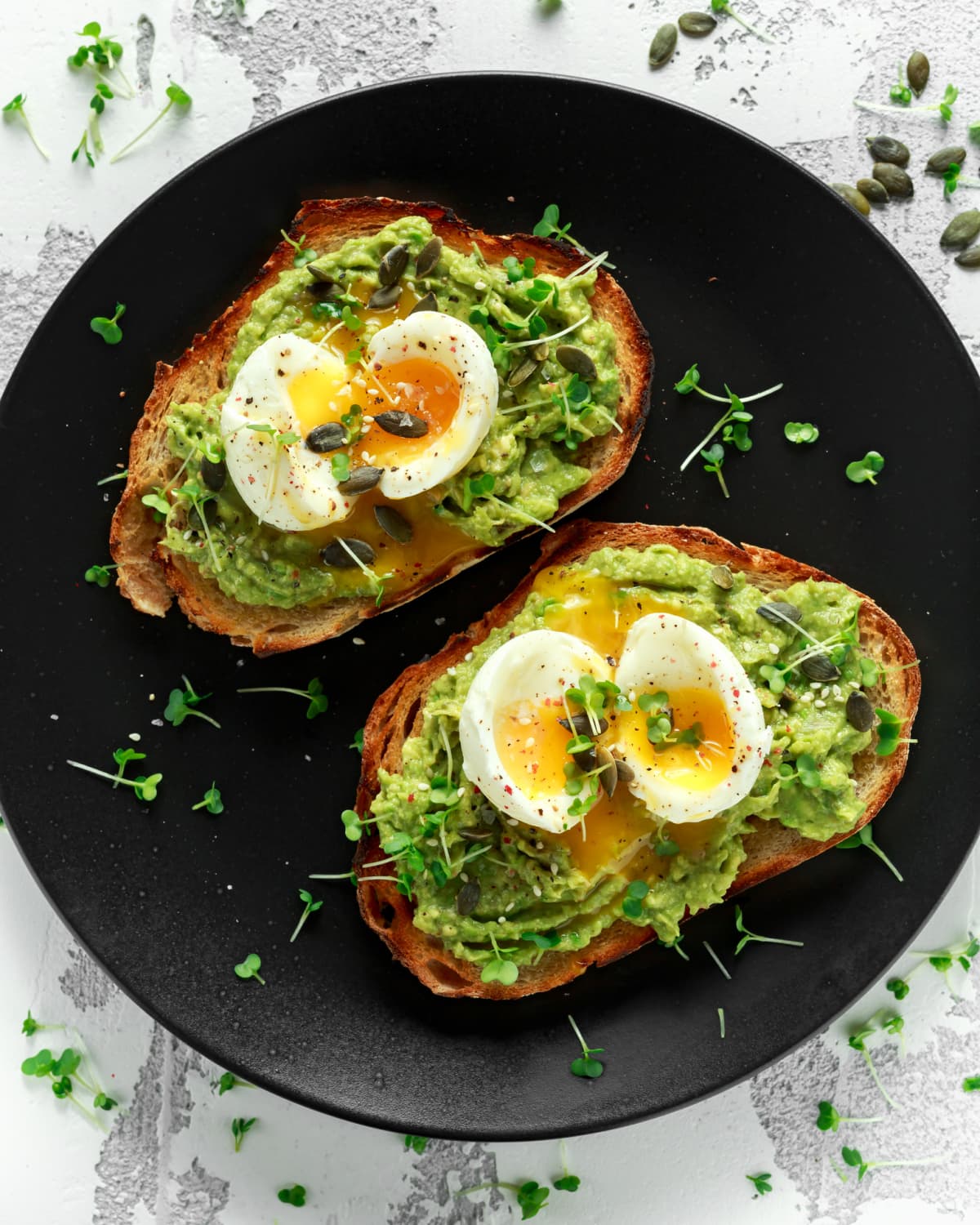 Two slices of toast with avocado and soft boiled eggs