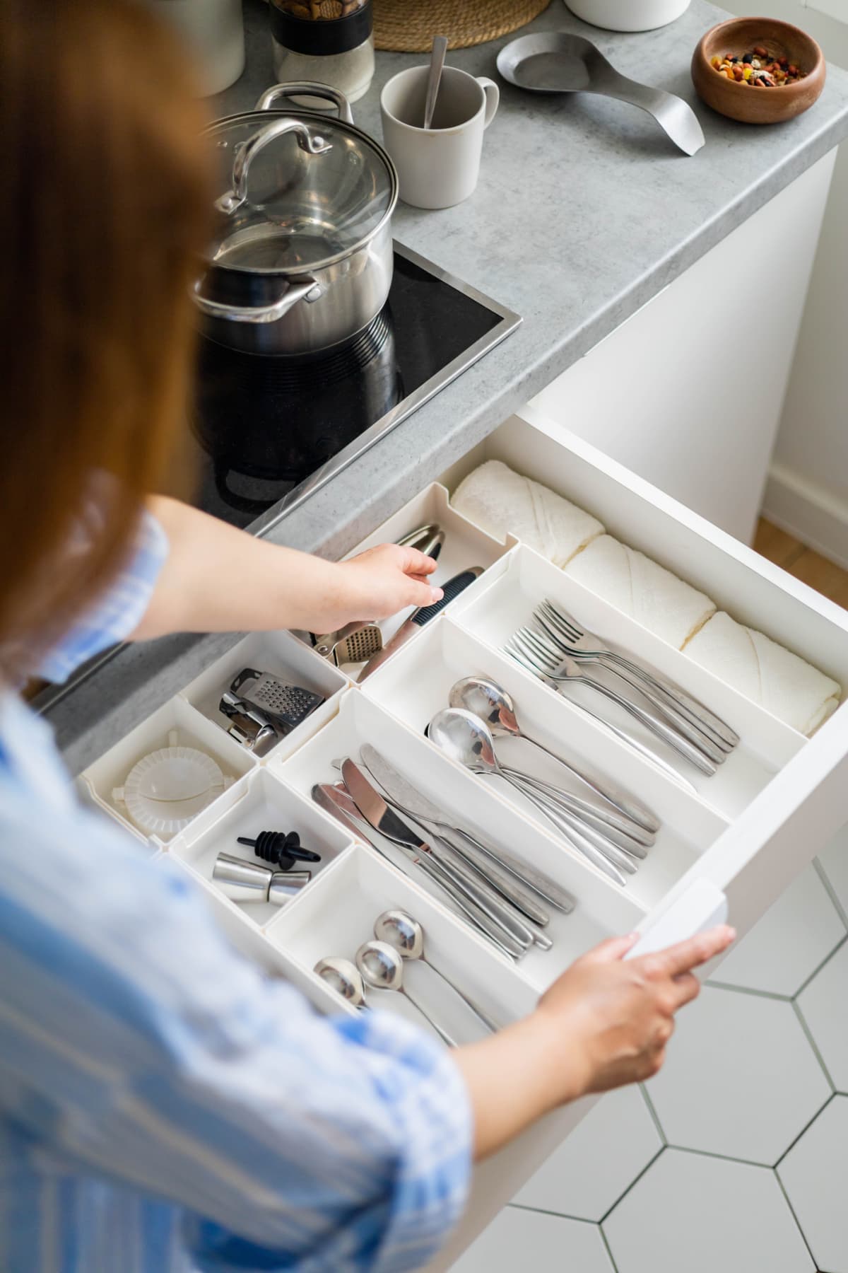Woman tidying up cutlery in kitchen drawer
