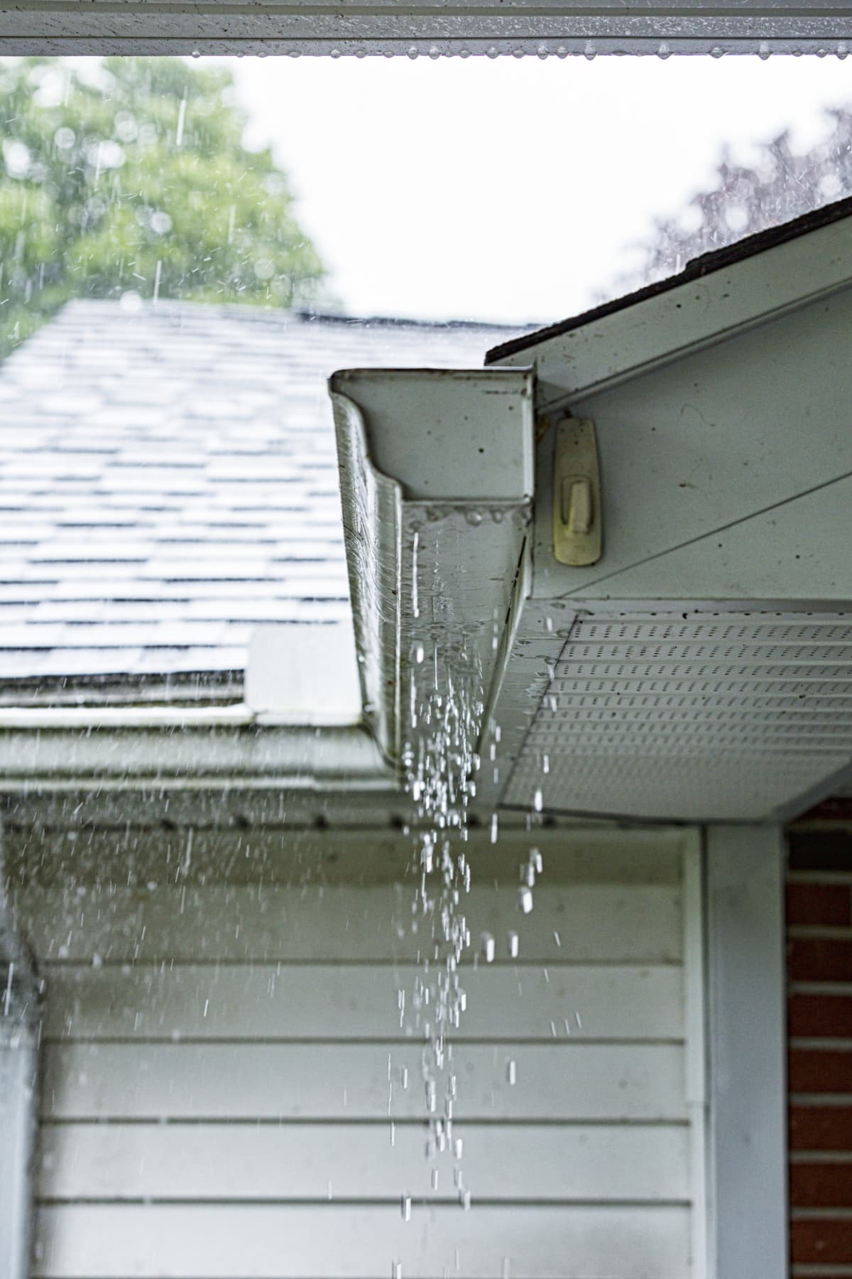 Rainwater overflowing aluminum gutters on a suburban residential colonial style house near Rochester, New York