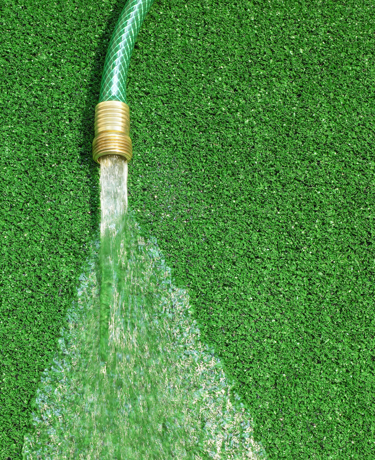 Hose with running water on artificial grass