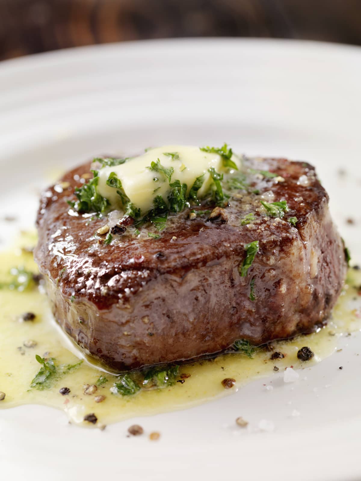 Medium rare fillet mignon steak with herb garlic butter on white plate