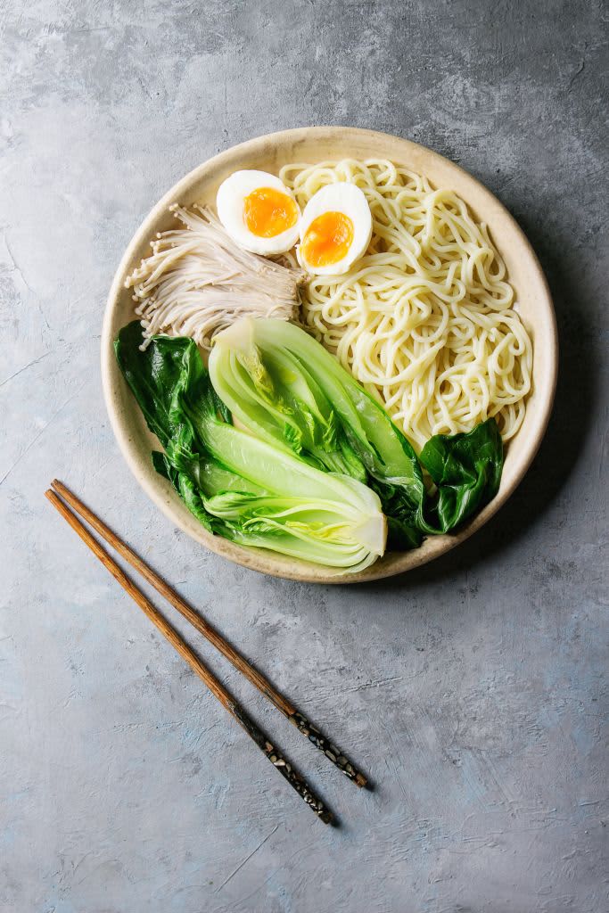 Bok choy in a bowl with noodles and egg